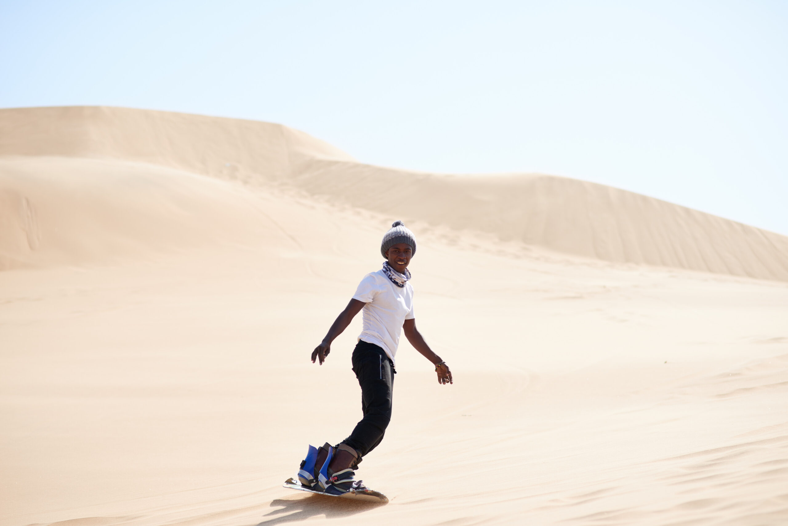 lets shred the sand. portrait of a young man sandboarding in the desert